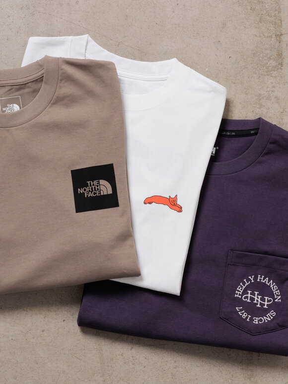 ゴールドウインオンラインストア公式 | 秋の気分をロンTから。 | THE NORTH FACEのベージュTシャツ、イラスト入りホワイトTシャツ、パープルのポケットTシャツを並べたワンポイントグラフィックトップスの展示