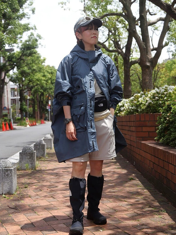 ゴールドウインオンラインストア公式 | STAFF STYLE | ブルーの防水レインポンチョにショートパンツとロングゲイターを合わせ、街歩きやフェスを想定したアウトドアルックを着用したモデルの全身カット