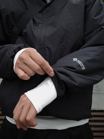 ゴールドウインオンラインストア公式 | STAFF PICKS AUTUMN OUTERWEAR STYLE | ブラックカラーのGORE-TEX WINDSTOPPER搭載シェルジャケットの袖口ディテール。ストレッチ性のあるインナーとのレイヤリングを見せた防風性の特徴がわかるアップ。