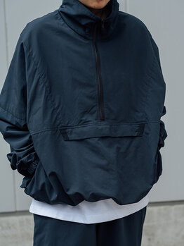 ゴールドウインオンラインストア公式 | STAFF PICKS AUTUMN OUTERWEAR STYLE | ネイビーカラーのハーフジップアノラックジャケットのフロントディテール。高めのスタンドカラーとゆったりしたシルエットが特徴のアップ。