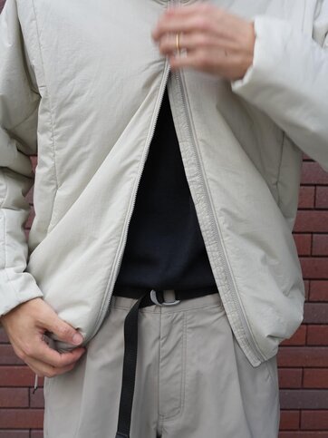 ゴールドウインオンラインストア公式 | STAFF PICKS AUTUMN OUTERWEAR STYLE | ライトベージュカラーのインサレーションジャケットのフロントディテール。軽量な中わた入りデザインと裾のドローコード仕様を確認できるアップ。