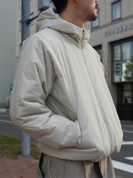 ゴールドウインオンラインストア公式 | STAFF PICKS AUTUMN OUTERWEAR STYLE | ライトベージュカラーのフード付きインサレーションジャケットのサイドディテール。ボリューム感のある中わたと立体的なフード形状がわかるアップ。