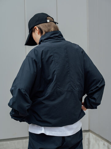 ゴールドウインオンラインストア公式 | STAFF PICKS AUTUMN OUTERWEAR STYLE | ネイビーカラーのアノラックジャケットを着用したバックスタイル。ゆとりのあるシルエットと軽量なナイロン素材の風合いが伝わる後ろ姿。